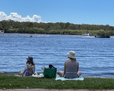 Family sitting by the river on Gympie Terrace Noosaville